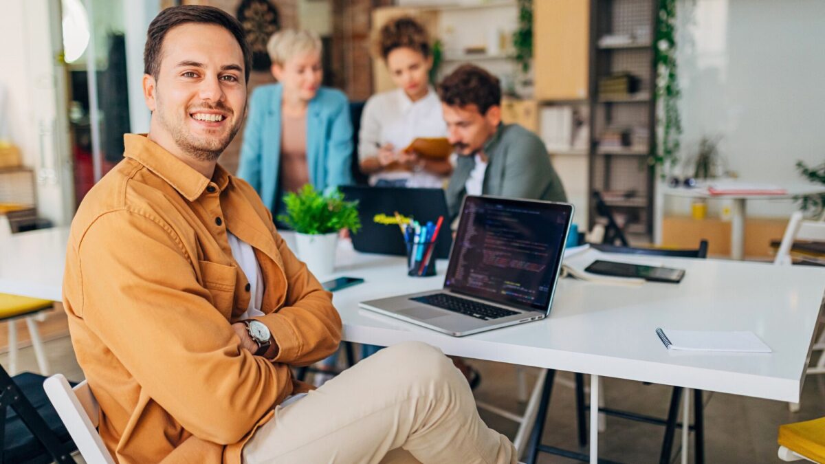 An IT support analyst in an office smiling while assisting Stockport businesses with the latest technology needs