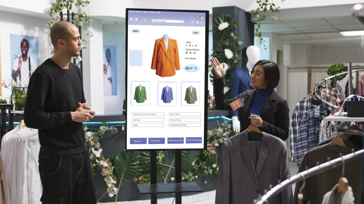 A woman guiding a male customer on digital signage displays